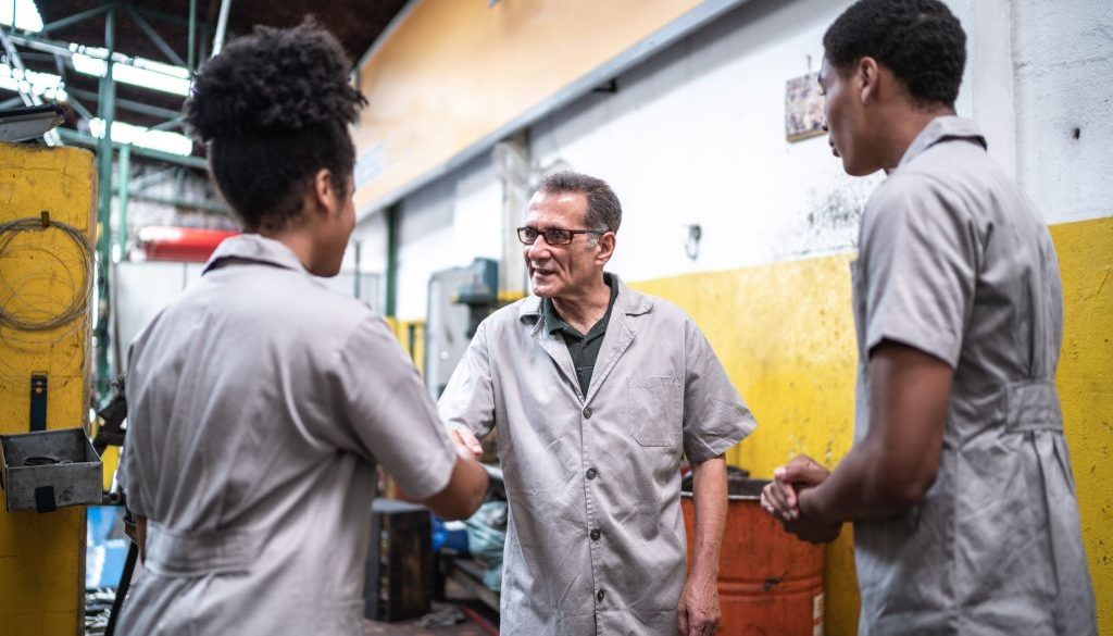 Auto mechanic man greeting his assistants on a repair shop