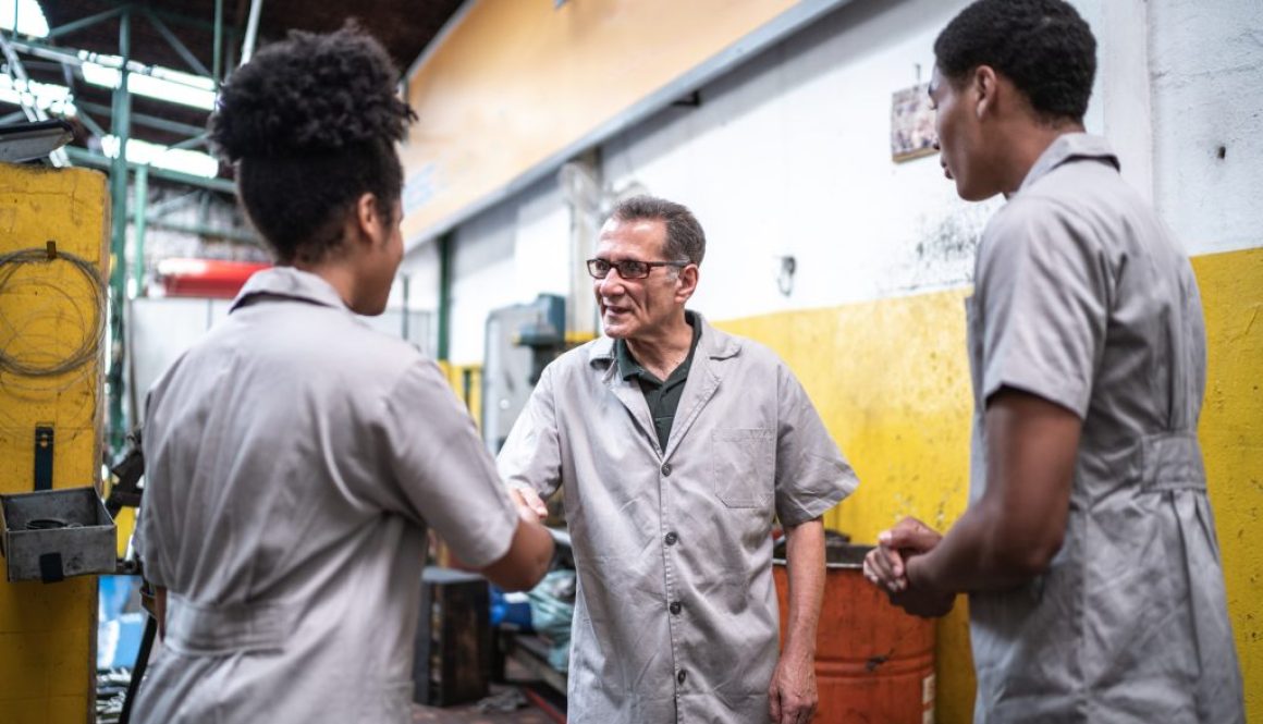Auto mechanic man greeting his assistants on a repair shop
